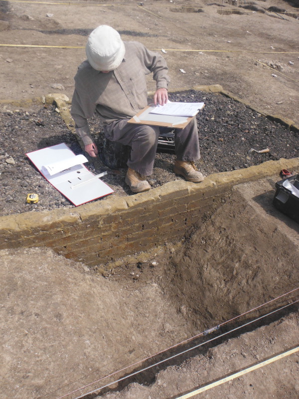 Excavation has begun in earnest - Richard records a slot over a medieval ditch cut through by a 20th century brick building