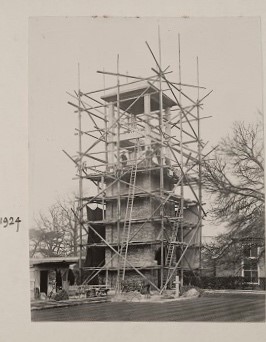 A building of a tower being built, surrounded by scaffolding. A note next to the image is states that this is from 1924. 