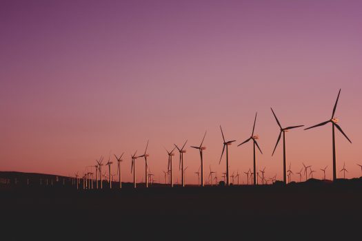 Row of wind turbines against sunset