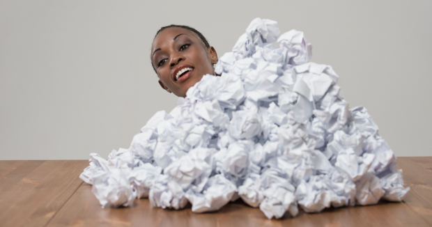 Person emerging from behind a stack of scrunches up paper