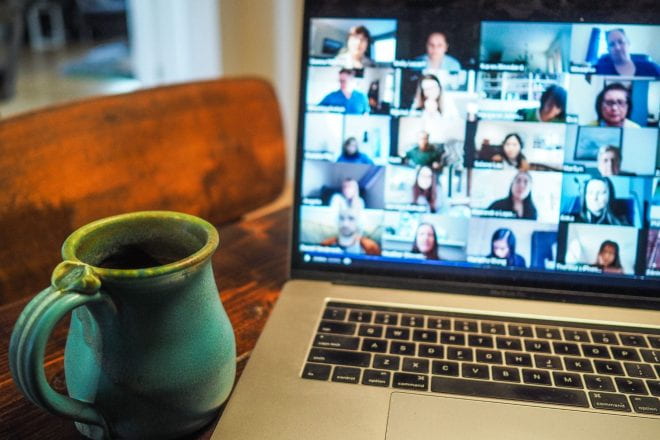 Blue mug next to a laptop showing a Zoom call