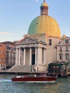 a boat on a canal in Venice in front of a grand buliding with a domed top