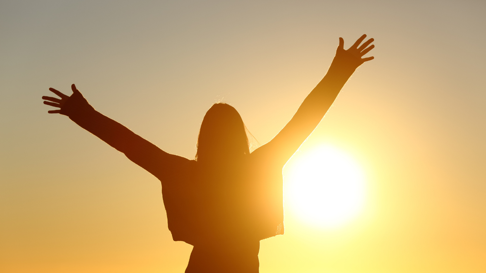 Image of a girl with hands in the air facing the sun.