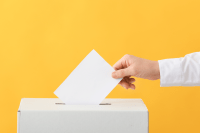 An image of someone voting, they are putting their voting care into a box